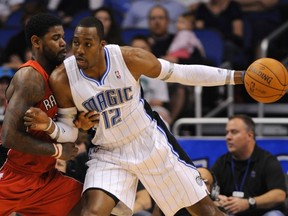 Dwight Howard shields the ball from Raptors' Amir Johnson during Sunday evening's game in Orlando. The Magic rallied for a 102-96 win. (Reuters)