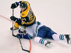 Boston Bruins left wing Brad Marchand lands on Vancouver Canucks defenceman Sami Salo during their game in Boston on January 7, 2012. (REUTERS/Adam Hunger)
