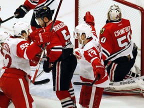 Detroit Red Wings' Pavel Datsyuk (13) celebrates his game-winning goal with teammate Jonathan Ericsson (52) on Chicago Blackhawks' goalie Corey Crawford (50), while Blackhawks' Steve Montador (5) skates away, during the overtime period of their game in Chicago on January 8, 2012. (REUTERS/Jim Young)