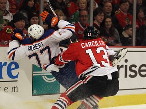 Blackhawks’ Daniel Carcillo take Oilers Tom Gilbert into the boards during Monday's game in Chicago. (Jonathan Daniel/AFP)