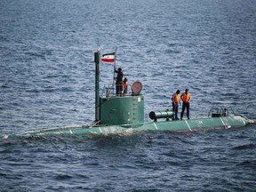 Military personnel place a flag on a submarine during the Velayat-90 war games by the Iranian navy in the Strait of Hormuz in southern Iran December 27, 2011. (REUTERS/IIPA/Ali Mohammadi)