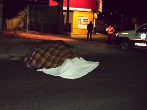 Blankets cover the bodies of dead men on a street in Zitacuaro in the state of Michoacan on January 9, 2012. Police found thirteen semi-naked bodies piled one atop the other outside a convenience store in western Mexico on Monday, local authorities said. (REUTERS/Quadratin)