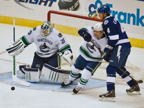 Canucks goaltender Cory Schneider clears the puck as defenceman Keith Ballard pushes away Lightning captain Vincent Lecavalier in Tampa, Fla., Jan. 10, 2012. (STEVE NESIUS/Reuters)