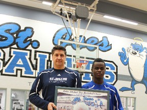 St. Joseph Saints head coach Mike Kornak and player Kavenanbutako (Kevin) Dimonekene pose with a poster of Father Michael Troy. (Supplied)