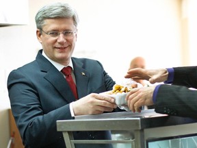 Prime Minister Stephen Harper serves poutine in a snack bar in Saguenay, Quebec on January 17, 2012. (REUTERS/Mathieu Belanger)
