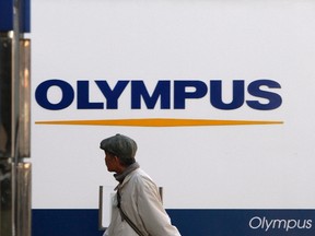 A man walks past signboards of Olympus Corp outside its showroom in Tokyo Jan. 12, 2012. REUTERS/Toru Hanai