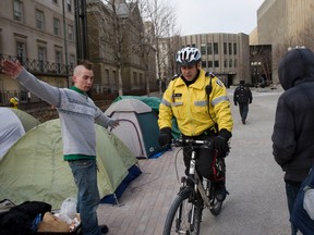 Occupy Toronto protesters give wide berth to a police officer patrolling the area of 361 University Court House and Toronto City Hall Wednesday morning. (STAN BEHAL/Toronto Sun)