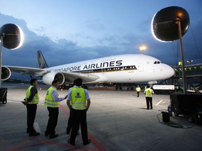 Members of the ground look at the Airbus A380 superjumbo, illuminated by floodlights, after it landed at Singapore's Changi Airport October 17, 2007. (REUTERS)