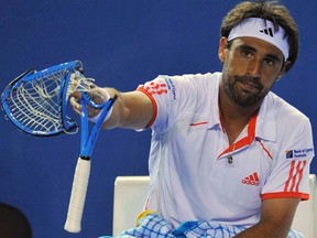 Marcos Baghdatis holds up a racquet that he smashed during a break in play at the Australian Open in Melbourne on Wednesday, Jan. 18, 2012. (REUTERS/Toby Melville)