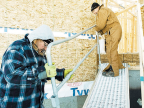 Kelly La Plante (right) and Jack Super, with Tigerpaw Safety Systems, install a safety ramp at a job site on the Newcastle development east of 127 Street on Wednesday. Both men bundled up against a -40 C windchill.