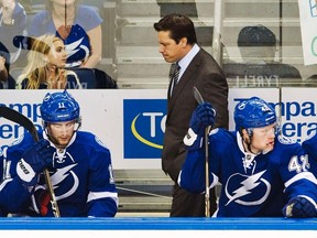 Tampa Bay Lightning head coach Guy Boucher paces the bench behind Tom Pyatt and Dana Tyrell during the first period of their NHL hockey game against the Vancouver Canucks in Tampa, Florida, Jan. 10, 2012.  (REUTERS/Steve Nesius)