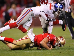 New York Giants cornerback Aaron Ross (top) flies over a sliding San Francisco 49ers quarterback Alex Smith during the fourth quarter of the  NFC championship game at Candlestick Park on Sunday. (Reuters)