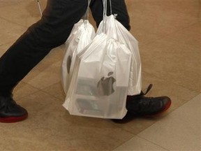 A man carries packs of Apple iPhone 4S, with each pack containing five sets, outside an Apple store in Hong Kong Nov. 11, 2011. Bobby Yip/REUTERS