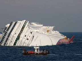 A vessel (bottom) sails past the cruise liner Costa Concordia, which ran aground off the west coast of Italy, at Giglio island Jan. 28, 2012. (REUTERS/Darrin Zammit Lupi)