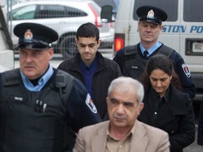 Mohammad Shafia (front), his wife Tooba Mohammad Yahya (R) and their son Hamed, are escorted by officers at the Frontenac courthouse in Kingston on Jan. 25. (REUTERS)