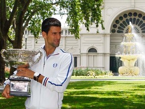 Novak Djokovic holds the men's singles winner's trophy in Melbourne on Monday, Jan. 30, 2012. (REUTERS/Daniel Munoz)