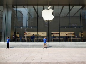 Employees stand outside the third Apple Store in Shanghai in this Sept. 21, 2011 file photo.     REUTERS/Aly Song/Files