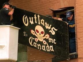 Members of the Biker Enforcement Unit rip the Outlaws sign off the wall of the London, Ont. clubhouse as part of a province-wide raid in this QMI Agency file photo. (MORRIS LAMONT/QMI Agency Files)