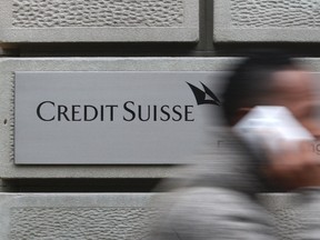 A man uses his cell phone as he walks past a branch of Swiss bank Credit Suisse in Zurich, January 31, 2012. REUTERS/Christian Hartmann