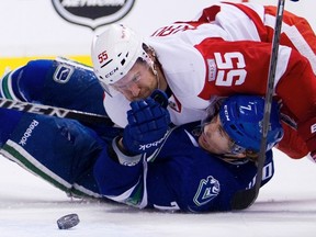 Canucks forward David Booth is knocked to the ice by Red Wings defenceman Niklas Kronwall at Rogers Arena in Vancouver, B.C., Feb. 2, 2012. (BEN NELMS/Reuters)