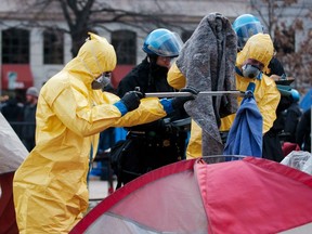 Workers in protective hazmat suits clear the belongings of protesters from the Occupy DC protest movement at the Occupy DC encampment in McPherson Square, Washington Feb. 4, 2012.    REUTERS/Jonathan Ernst