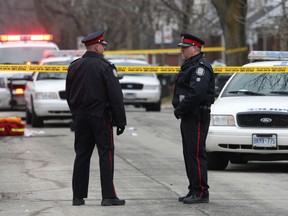 Toronto Police officers stand on Milverton Ave. Friday after a man was shot dead. (CRAIG ROBERTSON/Toronto Sun files)