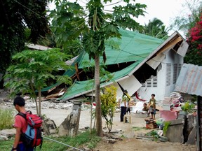 Resident carry what was left of their belongings after their house collapsed from an earthquake in Negros Oriental, central Philippines February 6, 2012. (REUTERS/Bongbong Woo Tadifa)