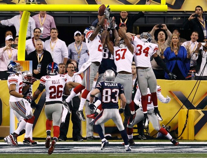 Wide receiver Victor Cruz (80) of the New York Giants and kicker Lawrence  Tynes (9) of the New York Giants hold the championship trophy at the end of  Super Bowl XLVI on