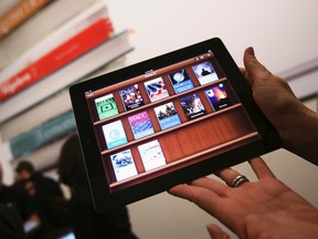 A woman holds up an iPad with the iTunes U app after a news conference introducing a digital textbook service in New York January 19, 2012.  REUTERS/Shannon Stapleton