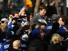 New York Giants quarterback Eli Manning holds up the Vince Lombardi Trophy as he walks through the crowd while attending a ceremony in honour of the Giants' win in Super Bowl XLVI, Tuesday at City Hall Plaza in New York. (REUTERS)