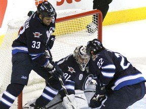 Winnipeg Jets RW Chris Thorburn (22) and Winnipeg Jets defenceman Dustin Byfuglien help Winnipeg Jets goaltender Ondrej Pavelec keep the puck out during NHL action last season. A chance to get on the waiting list for Jets season tickets occurs on Friday. (JASON HALSTEAD/WINNIPEG SUN FILES)