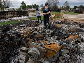 Tyson Houle, right, his wife Angela Houle and their son Seth, 14 months, revisit the remnants of their home in northwest Slave Lake, Alta., on Thursday, June 16 2011. The Houles were only waiting on technicalities to close the sale of their newly renovated home before the wildfires. Through his company, Bullitproof Construction Ltd., Tyson is involved in the reconstruction of Slave Lake. AMBER BRACKEN/EDMONTON SUN FILE PHOTO