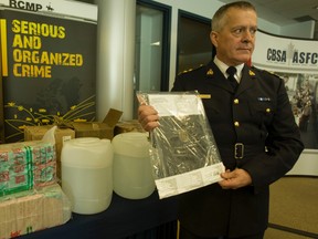 RCMP Supt. Rick Penney in command of the GTA’s drug bureau holds a kilo of hash in front of two barrels of the chemical GBL. (Jack Boland/Toronto Sun)