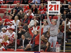 A fan holds up a sign congratulating the Red Wings on their NHL record-breaking 21st consecutive home victory after they defeated the Stars at Joe Louis Arena in Detroit, Mich., Feb. 14, 2012. (GREGORY SHAMUS/Getty Images/AFP)