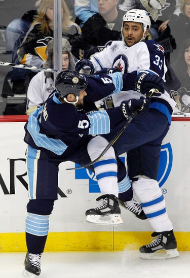 Pittsburgh Penguins Deryk Engelland (5) checks Winnipeg Jets Dustin Byfuglien in the first period of their NHL hockey game in Pittsburgh, Pennsylvania February 11, 2012. REUTERS/Jason Cohn (UNITED STATES - Tags: SPORT ICE HOCKEY)