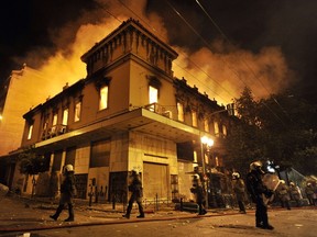 Police walk past by a burning building in Athens during massive clashes with protesters on February 12, 2012. (AFP PHOTO/LOUISA GOULIAMAKI)