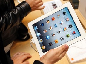 Customers discover the Apple's iPad 2 in a Paris Apple store after its official launch for direct purchase in France in this March 25, 2011 file photo. REUTERS/Charles Platiau/Files