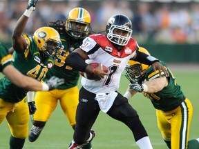 Rod Davis, left, and Greg Peach right, shown here running down Henry Burris in a game against the Stampeders last season, likely won't be in the Eskimos lineup Tuesday morning, barring any last-minute deals. (QMI Agency file)