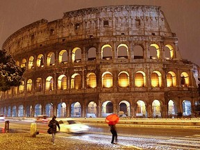 People walk during a heavy snowfall in front of the Colosseum in downtown Rome on Friday, Feb. 10, 2012. Italy's difficult economic situation would prevent the government offering the necessary financial guarantees for a possible Rome Olympics. (REUTERS/Max Rossi)