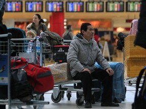 A man sits on a luggage cart after his flight was cancelled at Ruzyne Airport in Prague in this December 1, 2011 file photo. (REUTERS/David W Cerny)