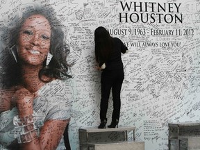 A Filipino fan writes a message on a tribute wall for the late American singer-actress Whitney Houston that is displayed inside a mall in Manila February 15, 2012. REUTERS/Romeo Ranoco