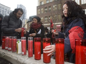 Gabriela Rodriguez lights one of 12 candles remembering migrant workers  who tragically lost their lives in a near Stratford, Ont. on Feb. 6. She was one of about 50  people supporting the group Justicia for Migrant Workers (J4MW)  demanded inquest into the crash and two other workers who came from Jamaica and died in September 2010. (JACK BOLAND/Toronto Sun)
