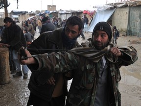 An Afghan man aims a sling shot toward US soldiers at the gate of Bagram airbase during a protest against Qur'an desecration on February 21, 2012 at Bagram about 60 kilometres (40 miles) north of Kabul. (AFP PHOTO/SHAH Marai)