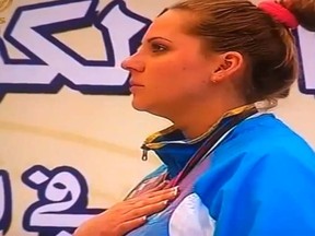Kazakhstan shooting athlete Maria Dmitrienko puts her hand to her chest while a parody anthem from the movie Borat plays at a medal ceremony in Kuwait on Thursday, March, 22, 2012. (Youtube video)