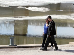 A couple strolls along the riverwalk at the Forks in Winnipeg Saturday. (BRIAN DONOGH/Winnipeg Sun)