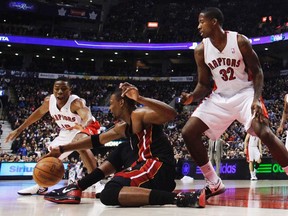 Miami Heat's Chris Bosh (centre) falls to the floor as Toronto Raptors' Ed Davis (right) and Ben Uzoh for the ball during the first half of Friday night's game at the ACC. (REUTERS)