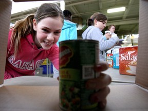 Magellan Jull, 13, pulls a tin of canned peas and carrots out of a box while sorting food on Monday. (LAURA PEDERSEN, Toronto Sun)