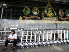 A Thai woman sits in front of a banner with portraits of Thailand's King Bhumibol Adulyadej at the Suvarnabhumi Airport in Bangkok July 5, 2010. (REUTERS/Chaiwat Subprasom)