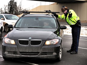 Sheriff Boulter checks the insurance and license of a driver.   PERRY MAH/EDMONTON SUN  QMI AGENCY