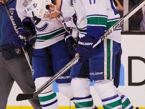 Canucks forward Mason Raymond (centre) is helped off the ice by teammates after suffering a back injury in last year's Stanley Cup final against the Bruins. (ADAM HUNGER/Reuters file photo)